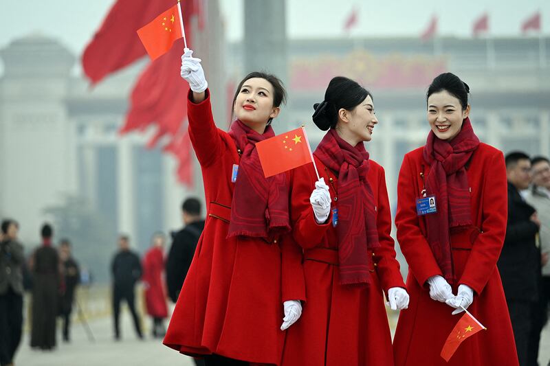 Attendants hold Chinese flags in Tiananmen Square following the closing session of the National People's Congress  in Beijing, March 11, 2025.