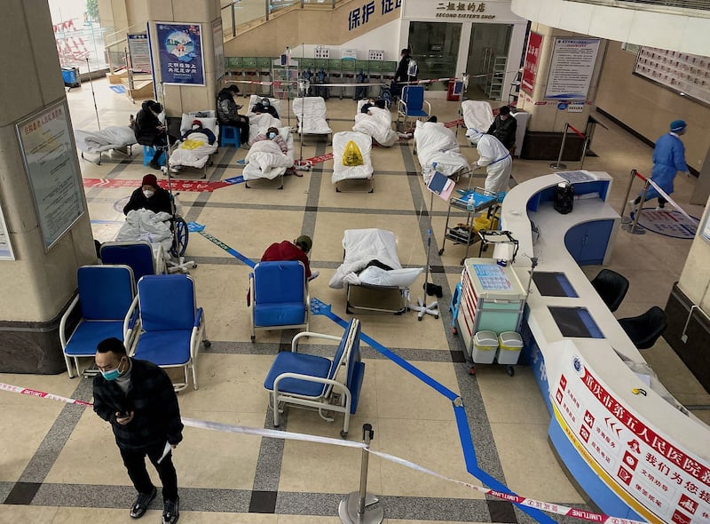 A man stands in front of a cordoned-off area, where COVID-19 patients lie on hospital beds, in the lobby of the Chongqing No. 5 People's Hospital in China's southwestern city of Chongqing on Friday, Dec. 23, 2022. Credit: AFP