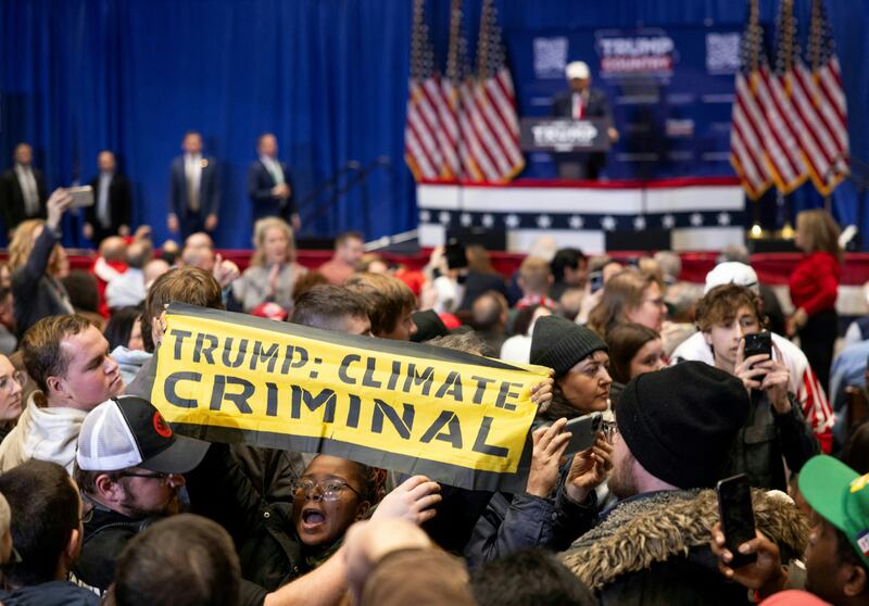 Climate protesters interrupt former US president and Republican presidential hopeful Donald Trump as he speaks at a "commit to caucus rally" in Indianola, Iowa, on Jan. 14, 2024.