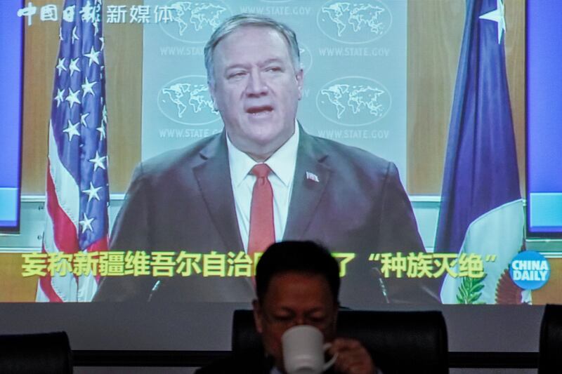 Xu Guixiang, a spokesperson for Xinjiang's Communist Party, drinks as a screen showing a footage of former U.S. Secretary of State Mike Pompeo, at the Ministry of Foreign Affairs office in Beijing, Monday, Feb. 1, 2021. Xu accused  Pompeo of trying to undermine Beijing's relations with President Joe Biden by declaring China's actions against the Uyghur ethnic group a "genocide."